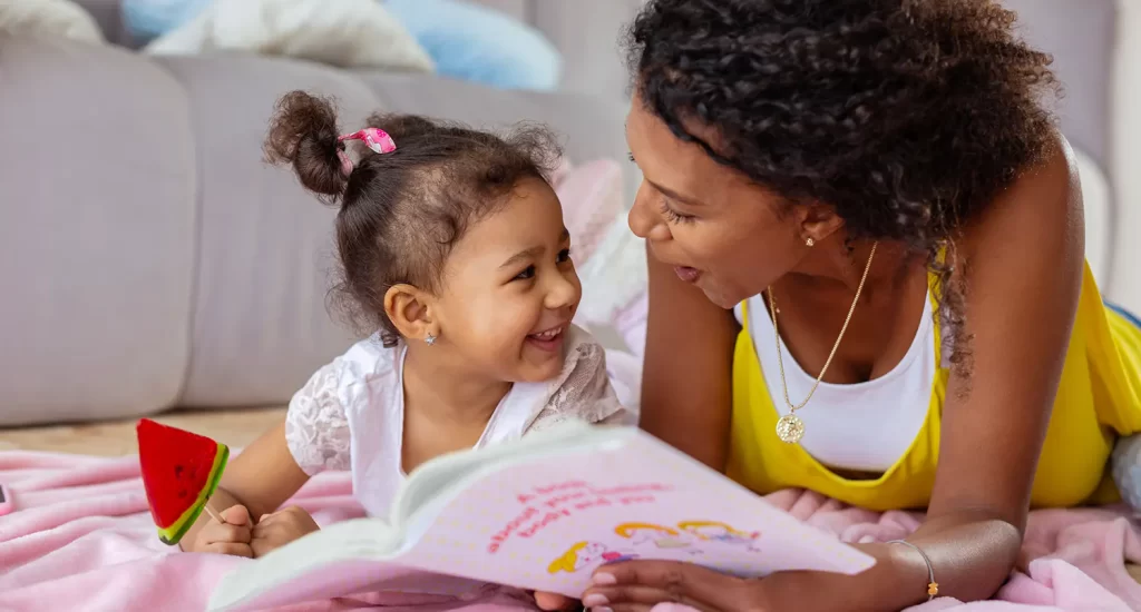 Mother and daughter reading book on floor